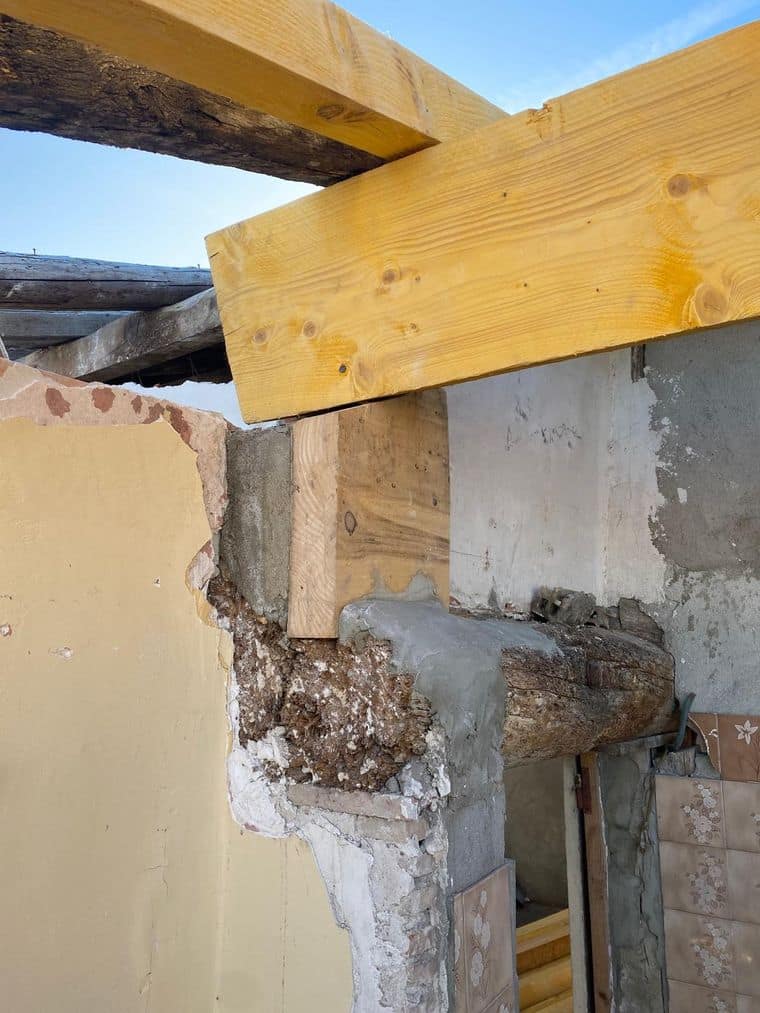 Tête de mur ancien dégarnie, poutre d’origine et bois neuf en appui au-dessus d’une baie