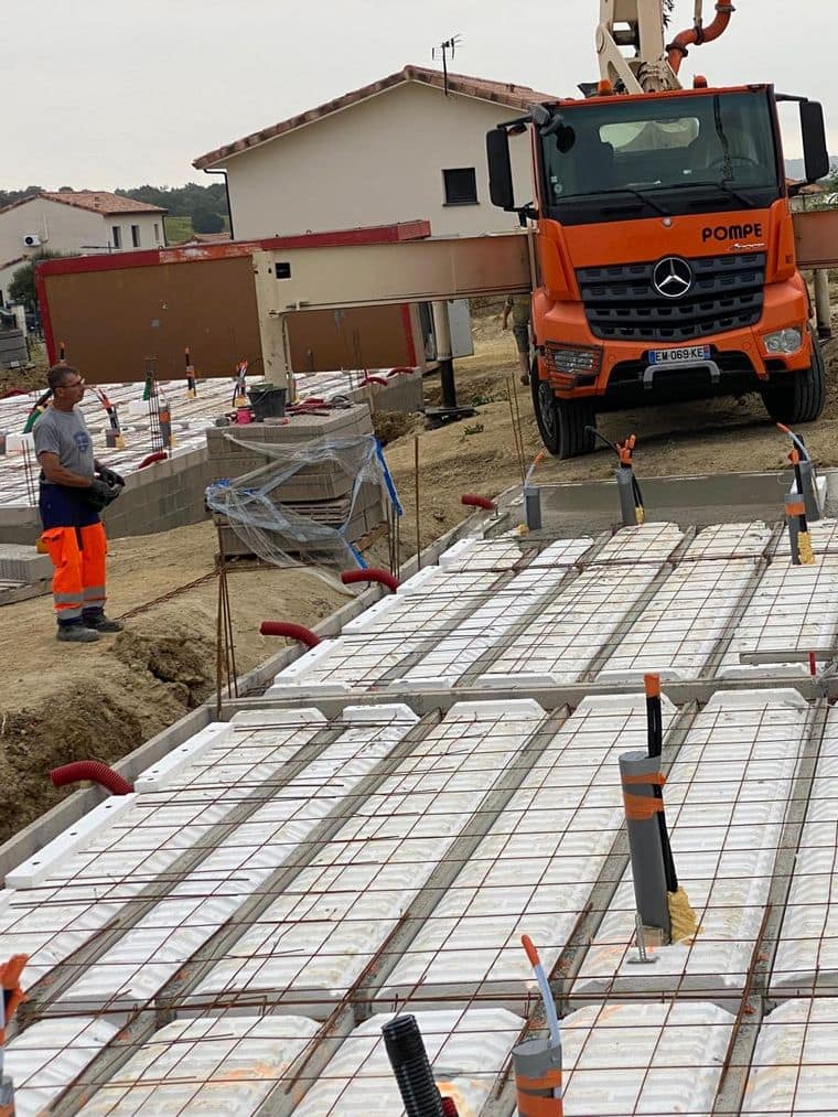 Coulage d'une dalle à la pompe à béton sur un plancher hourdis armé, trois compagnons au tirage