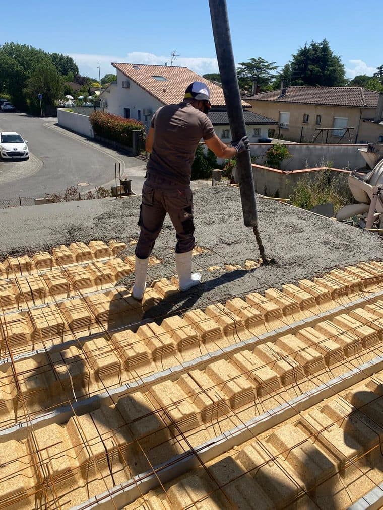Compagnon guidant la manche de la pompe à béton pendant le coulage d’un plancher en hourdis terre cuite