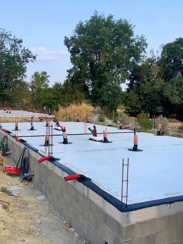 Dalle béton achevée sur soubassement en blocs, attentes de chaînage vertical et réservations de réseaux en place