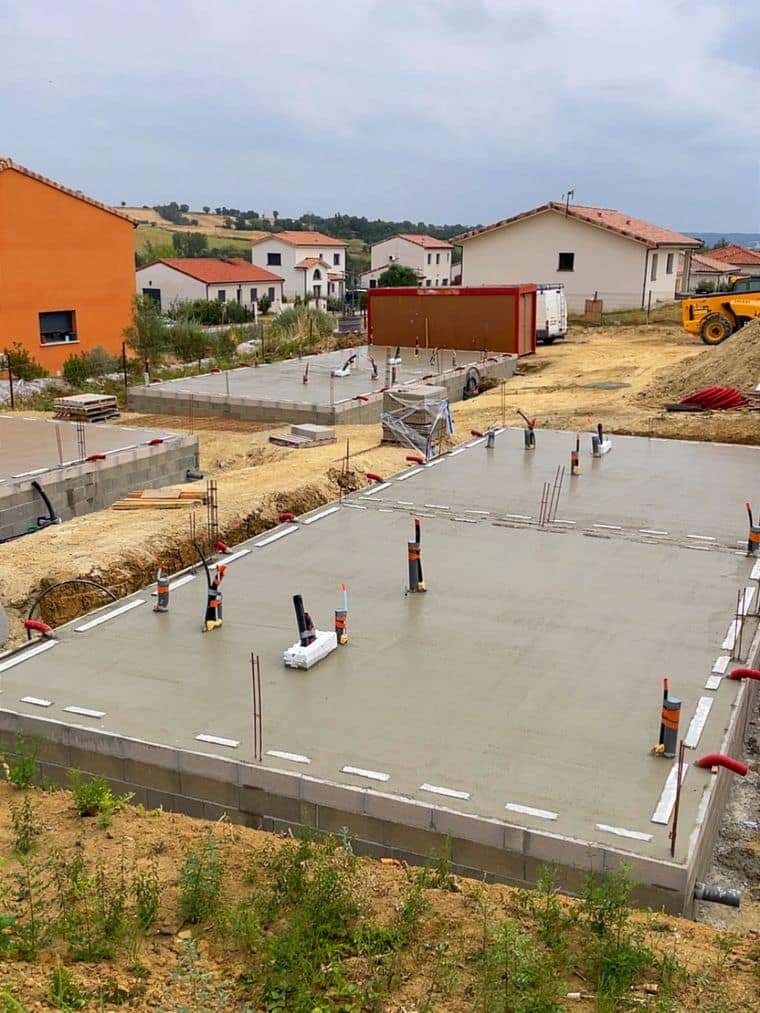 Deux dalles béton terminées avec réservations repérées, maisons voisines en arrière-plan