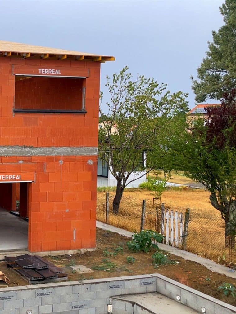 Maison en brique achevée en élévation, charpente posée et linteaux apparents