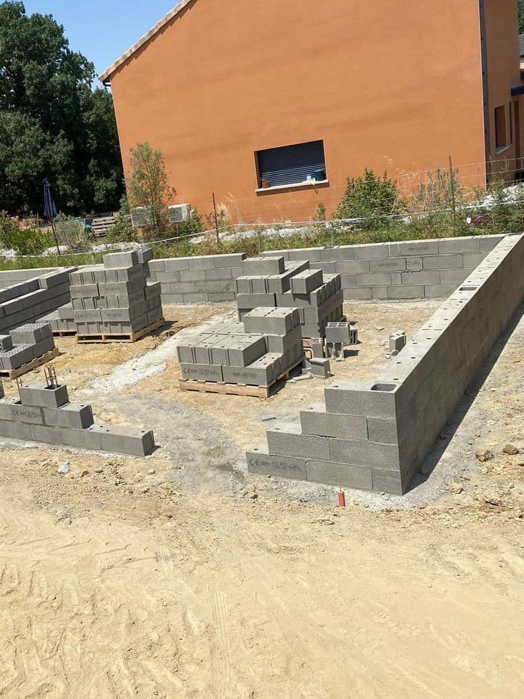 Soubassement en blocs béton en cours de montage sur les semelles, murs de refend du vide sanitaire en place
