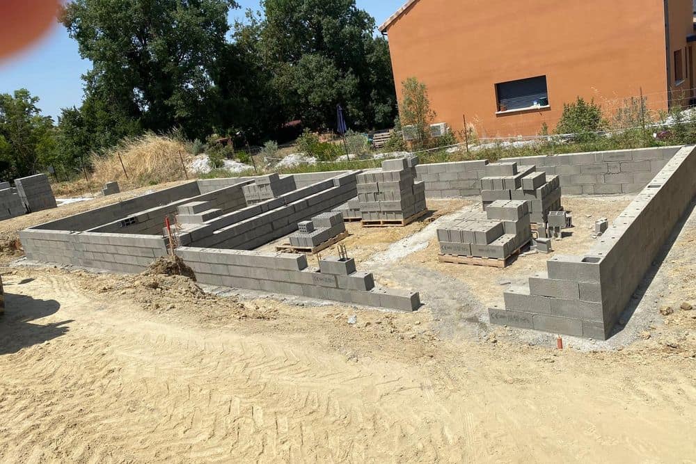 Soubassement en blocs béton en cours de montage sur les semelles, murs de refend du vide sanitaire en place