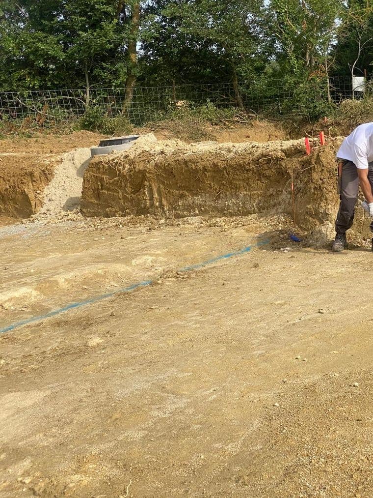 Compagnon vérifiant l’implantation en fond de fouille sur un terrain terrassé